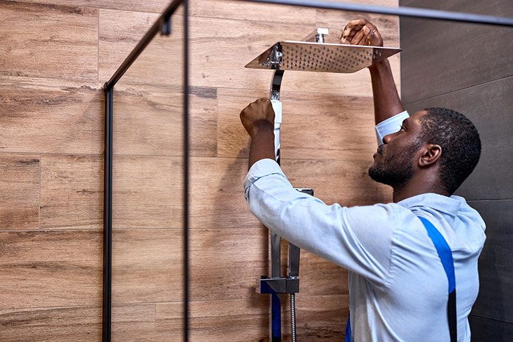 Bathroom installer fitting a rainfall shower head in new bathroom