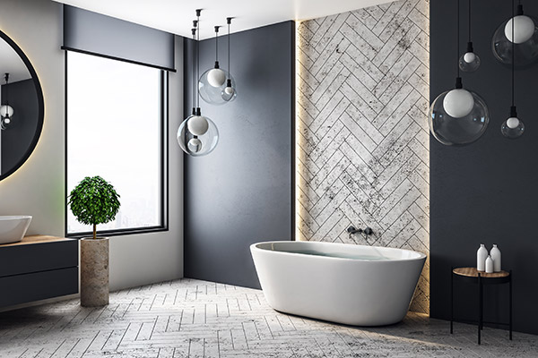 Free standing bath rub against a dark wall with a central highlight strip up the centre to the ceiling using the light grey herringbone floor tiles