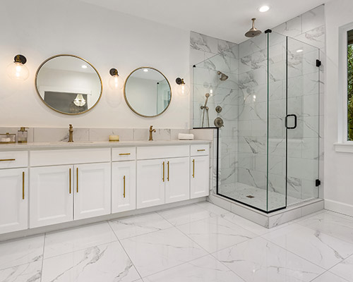 white and marble bathroom suite with shower unit and double sinks with gold accents